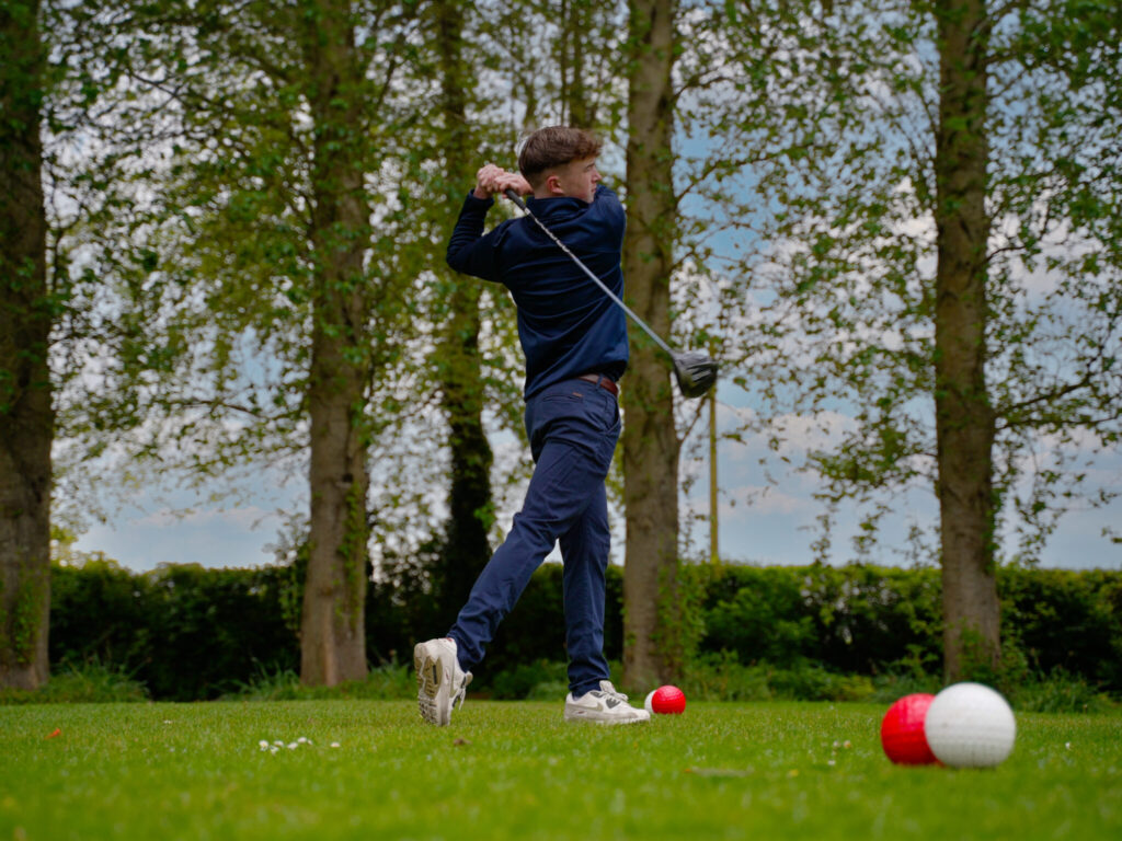 student hitting a golf ball